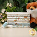 A stack of the fabrics included in the Woodland Heart FQ bundle, with leaves and flowers and a butterfly and a fox plushie and thread.