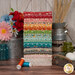 A collage stack of fabrics in the Farmer's Daughter Fat Quarter Set featuring various colors and prints in a farm table setting.