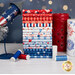 A stack of the patriotic fabrics included in the Firecracker Fat Quarter Bundle, with a jar and a rocket and a candle and thread.