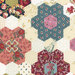 Cream fabric with multicolor faux patchwork hexagon flowers.