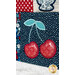 Close-up of a quilt featuring a square with two embroidered cherries with a blue stem on a navy background.