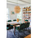 A modern dining room with a wooden table, six green chairs, a woven pendant light, and a bookshelf.
