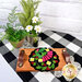 A shot of the completed Strawberry Zinger wool mat kit in black and bright colors, staged on a cutting board on a table with coordinating decor.