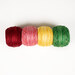 The Strawberry Zinger embroidery thread set, four spools of red, pink, yellow, and green thread, isolated on a white background.