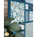 A side shot of the quilt featuring woodland prints in blue teal and cream with a plant in the foreground