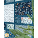 A side shot of the quilt featuring woodland prints in blue teal and cream with a tree in the foreground