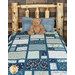 A patchwork quilt featuring forest animals in blue hues is staged on a wooden bed with a plush teddy bear. 