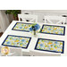 A wide shot of the four placemats on a white table with coordinating florals in a vase at the center.