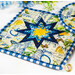A stylized shot of the square hot pad, taken at a slight angle and demonstrating details on the white and blue fabrics.