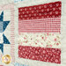 Up close of patchwork quilt featuring red and white patterns with floral and gingham designs.