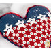 A heart-shaped fabric pillow featuring blue and red patterns with white star buttons.