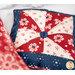 A colorful patchwork pillow featuring red, navy, and cream fabrics with floral and geometric patterns.