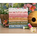 A stack of the fabrics in the Wild Honey FQ set, with flowers and a beehive and thread.
