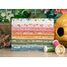 A stack of the fabrics in the Wild Honey F8 set, with flowers and a beehive and thread.