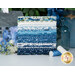 A stack of the fabrics featured in the Blueprint F8 set, with a metal house and flowers and vases and thread.