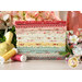 A stack of the fabrics featured in the Lyda Rose F8 set, with flowers and a pitcher and a bird and thread.