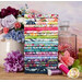 A stack of the fabrics in the Soulstice Fat Quarter Set with flowers and vases and a decanter and thread