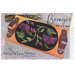 A floral embroidered design on a black mat, framed by a wooden holder with leather handles.