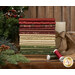 A stack of red, brown, tan, and green Christmas fabrics included in the Cozy Christmas FQ Set with pine branches and a candle and ribbon and thread.