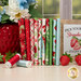 A stack of fabrics included in the Berry Besties FQ Bundle, with strawberries and flowers and a pot and a sign and thread.