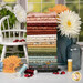 A stack of the fabrics included in the Love Bugs FQ Bundle, with flowers and a chair and jars and ladybugs and thread.