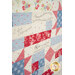 A colorful patchwork quilt featuring floral patterns and biblical text, in shades of red, blue, and white.