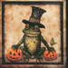 A whimsical frog wearing a top hat sits between two pumpkin jack-o'-lanterns.