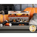 A stack of Halloween-themed fabrics in orange, black, and gray, alongside pumpkins and thread spools.