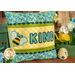 The finished June pillow wrap kit, a yellow wrap with blue and green scalloped borders and an appliqué bee beside appliqué letters that read 