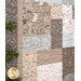 Close up of a quilt featuring a patchwork of muted tones with nature-inspired designs like deer and foliage.