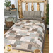 A patchwork quilt in earthy tones covers a bed, complemented by a textured pillow and surrounded by coordinating decor. 