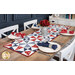 The completed Just a Sliver Tablerunner, colored in red, white, blue, and navy fabrics from the Grand Haven collection by Moda Fabrics, staged on a rustic wooden table and staged with coordinating napkins, four place settings, and red flowers in the center of the table.