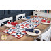 The completed Just a Sliver Tablerunner, colored in red, white, blue, and navy fabrics from the Grand Haven collection by Moda Fabrics, staged on a rustic wooden table and staged with coordinating napkins and four place settings.