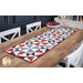 The completed Just a Sliver Tablerunner, colored in red, white, blue, and navy fabrics from the Grand Haven collection by Moda Fabrics, staged on a rustic wooden table with coordinating napkins and plates.