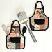 Two of the completed apron hot pads, colored in Halloween fabrics, staged on a white paneled background with kitchen utensils.