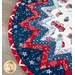 Close-up of a circular table topper design featuring red, white, and blue fabrics with star and truck patterns.