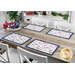 A dining table set with four red, white, and blue placemats, featuring patriotic motifs
