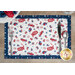 A patriotic placemat featuring red, white, and blue designs, surrounded by cutlery on a wooden table.