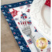 A decorative table setting featuring a fork on a patriotic-themed placemat and an ornate white plate.