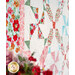 An angled shot of the left side of the quilt with a vase of red flowers peeking into frame, demonstrating fabric, piecing, and border details.