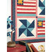 A close up on one of the pinwheel blocks, staged with coordinating pinwheels in blue and teal fabrics. 