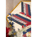 A stylized shot of the topper; the camera peers through coordinating flowers to look at the patchwork.
