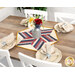 A shot of the table topper staged on a rustic table with four coordinating table settings with plates and napkins.