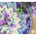 An aqua and purple quilted table mat featuring a zigzag design with purple flowers and geometric designs.