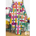The completed Picnic Quilt colored in vibrant fabrics from the Wild Abandon collection, staged on a quilt ladder with coordinating furniture and flowers.