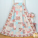 A colorful patchwork quilt featuring floral and pastel patterns, draped over a wooden ladder.