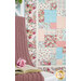 A cozy pink knitted blanket drapes beside an open book, with a floral patchwork quilt in the background.