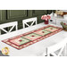The completed table runner made with log cabin blocks of red, pink, cream, and green floral fabrics from the Regal Rose collection, laying in the center of a white dining table with white chairs and coordinating decor.