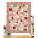The completed Easy as ABC and 123 Quilt - Regal Rose quilt featuring a patchwork design in pink, green, and cream hung on a white-paneled wall.