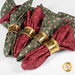 A shot of the four red and green reversible rose cloth napkins in gold, ornate napkin holders, spread across a white table.